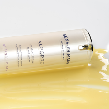 Perłowa butelka serum Sensum Mare Algopro z retinalem 0.08% leżąca na boku, otoczona złotym płynem.