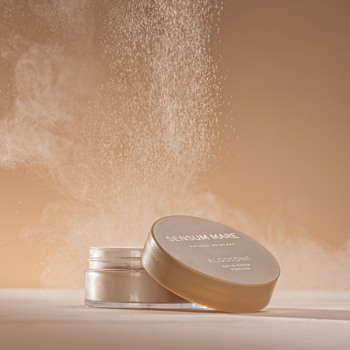 Transparentny puder sypki Sensum Mare Algotone, dwa beżowe opakowania, z chmurą satynowego pudru.