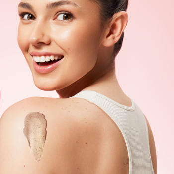 Uśmiechnięta kobieta z beBIO Naturalnym peelingiem do ciała strawberry matcha na ramieniu, widok z boku.