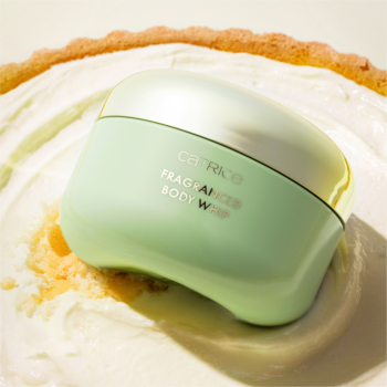 Catrice Fragranced Body Whip w jasnozielonym słoiku ze złotą zakrętką, osadzony w kremowym musie na tle ciasta.
