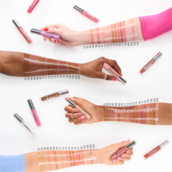 Różnorodne błyszczyki do ust w tubkach, ze swatchami na czterech różnych odcieniach skóry, widok z góry.