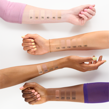 Cztery ramiona z różnymi odcieniami skóry pokazujące swatche podkładu w kilkunastu numerowanych odcieniach.