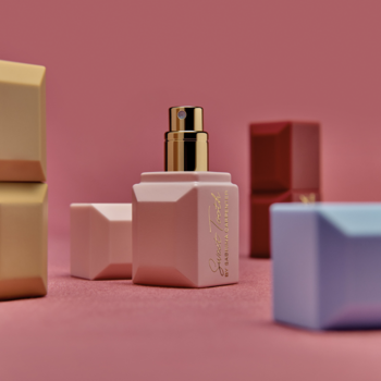 Różowy flakon perfum Sabrina Carpenter Sweet Tooth z złotym atomizerem, otoczony kolorowymi nakrętkami na różowym tle.