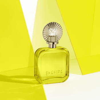 Perfumy Shakira w żółtej, prostokątnej butelce ze srebrnym, ozdobnym korkiem. Widok z przodu na żółtym tle.