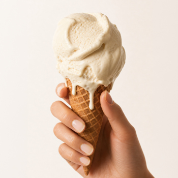 Dłoń trzyma rożek z topniejącymi lodami waniliowymi, symbolizujący odcień lakieru COOLNAILS Soft Vanilla.