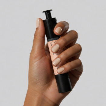 Dłoń z beżowymi paznokciami trzyma czarną butelkę lakieru-kuracji COOLNAILS Silk Beige z pompką.