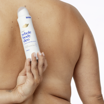 Widok z tyłu osoby, która trzyma biały dezodorant Dove Whole Body Deo, aplikując go na plecy. Na białym tle.
