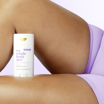 Biały sztyft Dove Whole Body Deo Lavender & Chamomile, oparty na ramieniu, widoczne fioletowe ubranie.