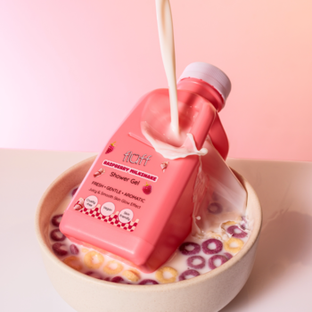 Różowy żel pod prysznic Fluff Raspberry Milkshake udający mleko wylewane do miski z kolorowymi płatkami.