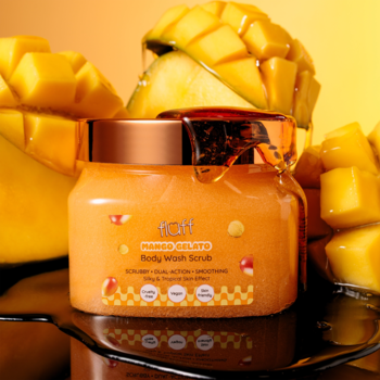 Fluff Mango Gelato peeling do mycia ciała, pomarańczowy, w słoiku z miedzianą zakrętką, tło z kawałkami mango.