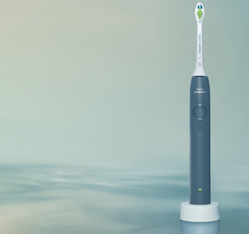 Soniczna szczoteczka do zębów Philips Sonicare, ciemnoniebieska z biało-zieloną główką, stoi na podstawce ładującej.