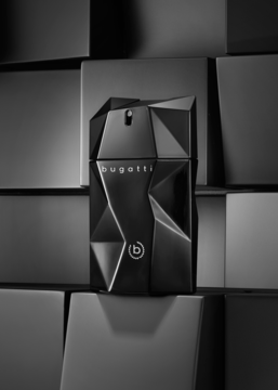 Czarny, fasetowany flakon Bugatti Unlimited Black, orientalno-drzewnej wody, na tle geometrycznych kostek.
