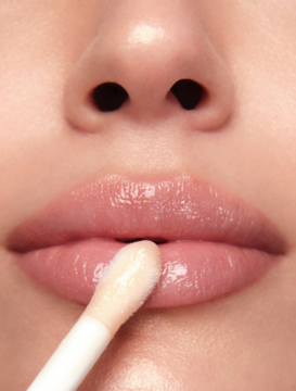 Zbliżenie: błyszczyk Pastel Plump Up Royal aplikowany na jasnoróżowe, lśniące usta, podkreślając ich objętość.