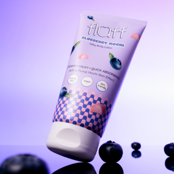 Balsam do ciała Fluff Blueberry Mochi w fioletowej tubce z borówkami, przechylony na błyszczącym fioletowym tle.