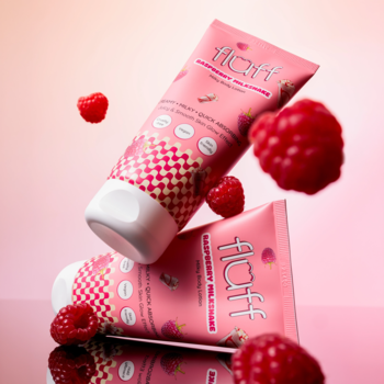 Dwie różowe tubki balsamu Fluff Raspberry Milkshake, z malinami, ustawione pod kątem na różowym tle.