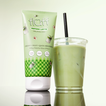 Zielony balsam Fluff Matcha Latte Milky Body Lotion w tubce, obok kubka mrożonej herbaty matcha.