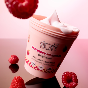 Różowy Fluff Raspberry Milkshake Body Yogurt w kubku, z kremem na wierzchu, otoczony malinami, na różowym tle.