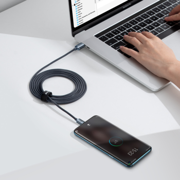 Pleciony kabel Baseus Crystal Shine USB-C 100W, 2m, ładujący telefon z laptopa na białym biurku.