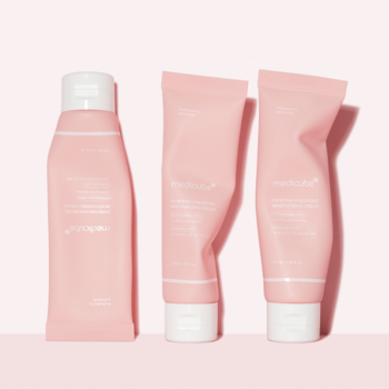 Trzy różowe tubki Medicube do pielęgnacji cery, dwie mniejsze z linii 'Red', stojące na jasnoróżowym tle, widok z przodu.