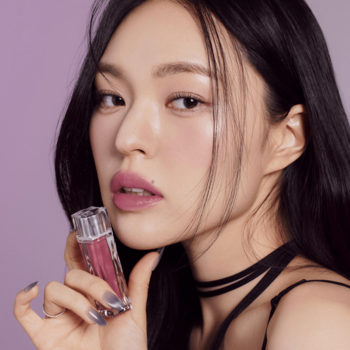 Muzigae Mansion Icy Glow Sway błyszczyk na ustach modelki, trzymającej fasetowany flakonik z bliska.