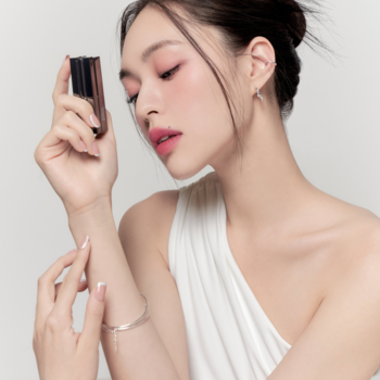 Kobieta trzyma matową pomadkę Muzigae Mansion Ruffle, prezentując jej aplikację i kolor na przedramieniu.