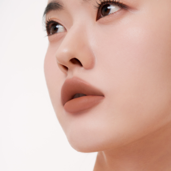 Zbliżenie na usta kobiety z lekkim tintem Muzigae Mansion Pride, matowe, brązowo-beżowe, rozmyte wykończenie.