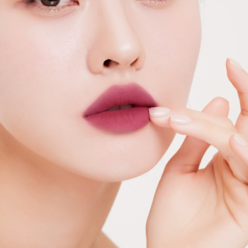 Muzigae Mansion lekki tint Spinel na ustach, matowe, rozmyte wykończenie, palec dotyka wargi.