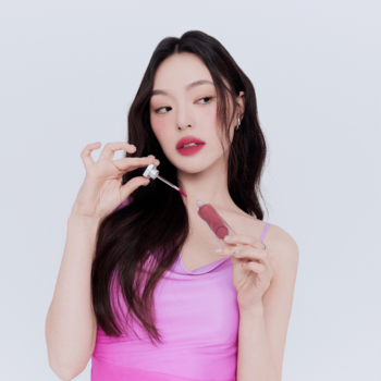 Kobieta w różowym topie aplikuje matowy tint do ust Muzigae Mansion Celeb, ukazując trwały kolor.