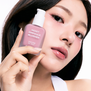 Różowy, kwadratowy róż do policzków MOIST AMPOULE BLUSHER z pompką, trzymany przez modelkę na białym tle.