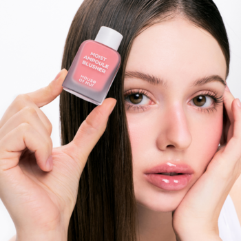 Kobieta trzyma różowy róż MOIST AMPULE BLUSHER House of Mouse; na jej policzku widoczny jest róż.