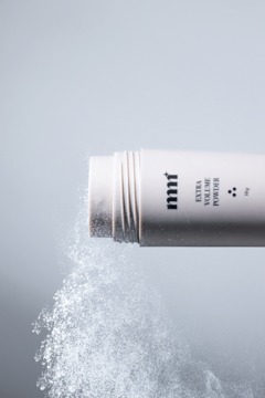 Poziome ujęcie: biały puder do włosów nnf Extra Volume Powder sypiący się z butelki, nadaje objętość.