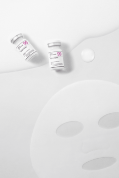 Dwie ampułki serum WHITE VITA C 99 i biała maska w płachcie na jasnym tle z kroplami płynu.