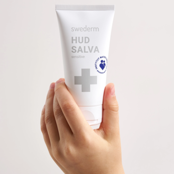 Biała tubka Swederm HUD SALVA Sensitive z szarym krzyżem, trzymana w dłoni, maść dla wrażliwej skóry.