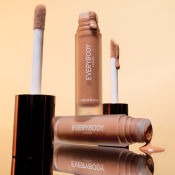 Płynny bronzer Everybody London Cool Sand: trzy buteleczki i aplikatory, rozlany produkt na odbijającym, ciepłym tle.