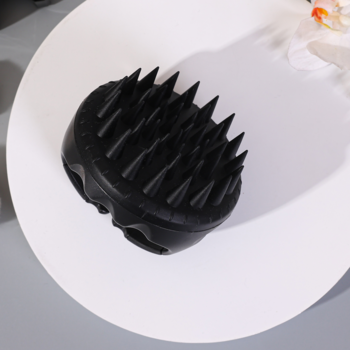 Czarna hipoalergiczna szczotka AURA do mycia i masażu głowy, z miękkimi silikonowymi wypustkami, widok z góry pod kątem.