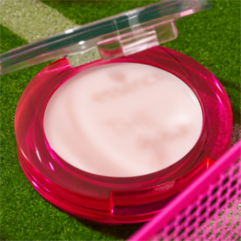 Różowy puder w kompakcie essence otwarty na zielonej murawie, ukazujący jasny kosmetyk z logo marki.