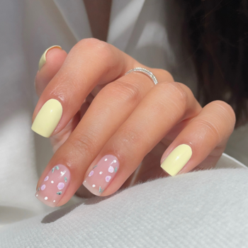 Bliskie ujęcie dłoni z manicure Semilac 122 Butter Yellow; żółte paznokcie i wzór w kropki. Klasyczny lakier.
