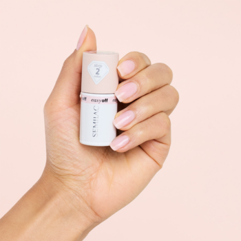 Dłoń trzyma buteleczkę Semilac Easy Off L02 Milky Pink z etykietą "2", paznokcie pomalowane mleczno-różowo.