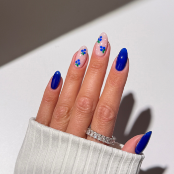 Dłoń z manicure Semilac Jelly Blueberry: intensywnie granatowe paznokcie i jeden z delikatnymi, błękitnymi kwiatami.