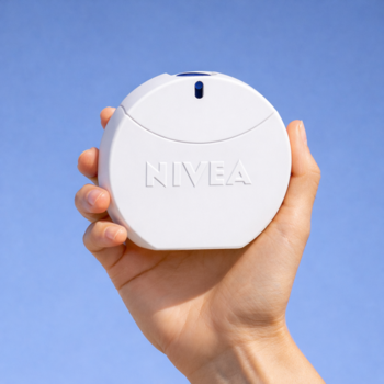 Biała, okrągła Nivea Creme Woda toaletowa w dłoni na tle błękitnego nieba. Otulający zapach ukochanego kremu.