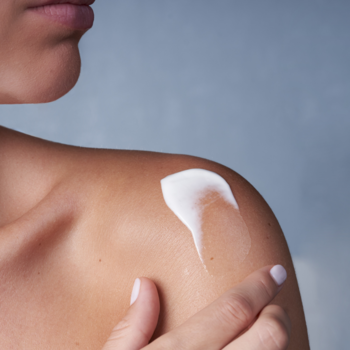 Uriage olejek w kremie do skóry suchej i atopowej. Bliskie ujęcie dłoni nakładającej produkt na ramię.