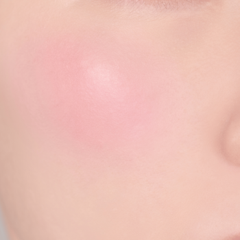 Zbliżenie na policzek z nałożonym różem do policzków w delikatnym, pudrowym odcieniu pastelowego różu.