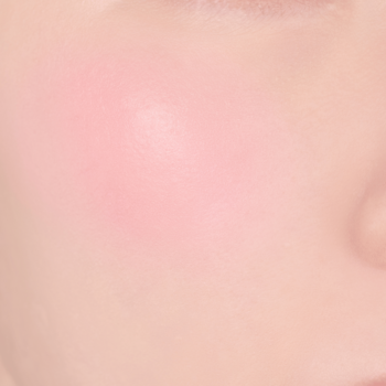 Zbliżenie na policzek z delikatnym różowym rumieńcem, tworzącym naturalny i świeży makijaż na jasnej skórze.