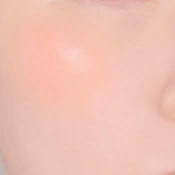 Makro ujęcie na skórę policzka z delikatnym różem, imitującym naturalny rumieniec, świeży i promienny wygląd.