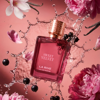 SWEET VELVET LA RIVE EDP, różowa butelka perfum ze złotym korkiem, otoczona kwiatami, czarnymi porzeczkami i wodą.
