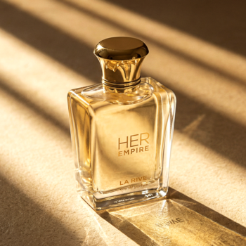 Perfumy HER EMPIRE LA RIVE w złotej butelce z ozdobną nakrętką, widok z przodu, na jasnym beżowym tle.