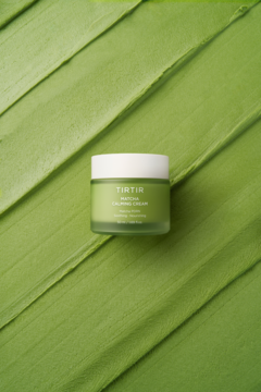 TIRTIR Matcha Calming Cream, zielony słoiczek z białą pokrywką, na tle zielonych pociągnięć kremu.