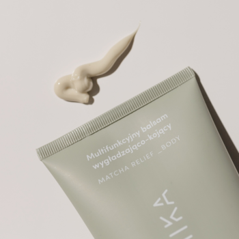 Polemika Matcha Relief _Body balsam do ciała, jasnozielona tuba z wyciśniętym beżowym kremem na jasnym tle.