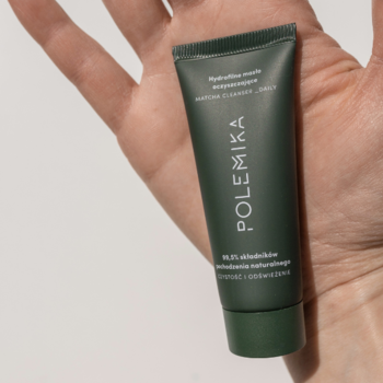 Ujęcie z bliska: matowa, ciemnozielona tubka masła oczyszczającego Polemika Matcha Cleanser Daily w otwartej dłoni.