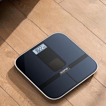 Czarna waga analityczna RENPHO Elis Solar 2, z widocznym cyfrowym wyświetlaczem, na drewnianej podłodze.